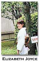 color photograph of Elizabeth Joyce, facing to the left next to a tree