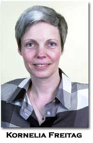 a white person in a checked shirt and silver hair smiles at the camera