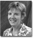 A black and white headshot of Jeanne Heuving. She is wearing a floral shirt and her hair is styled short.