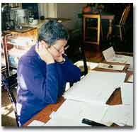 photograph at Martha King working at a table with papers strewn across it
